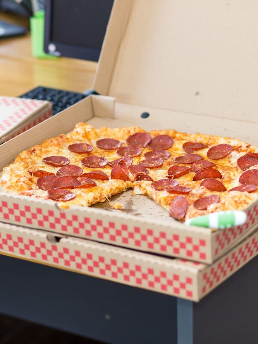 Pepperoni pizza in an open box on a desk